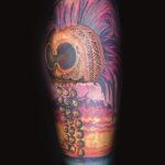 surrealism tattoo of a skull with beads over a tropical sunset by donavan moore