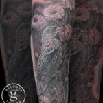 A bird and daises black and grey realism tattoo by Donavan Moore.
